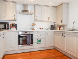 A kitchen with white cabinets a stainless steel oven a microwave a kettle and a sink at Trelowth Chapel in Polgooth