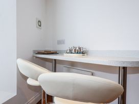 A kitchen counter with two white bar stools and a tray with metal teapots and cups at Trelowth Chapel in Polgooth