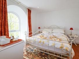 A bedroom with a metal bed frame floral bedding and red curtains at Trelowth Chapel in Polgooth