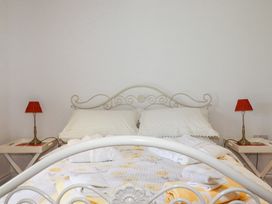 A bedroom with a white metal bed frame white pillows and side tables with red lamps at Trelowth Chapel in Polgooth