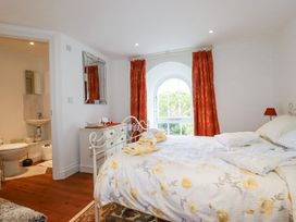 A bedroom with a bed covered with floral bedding and towels with a window with orange curtains at Trelowth Chapel in Polgooth