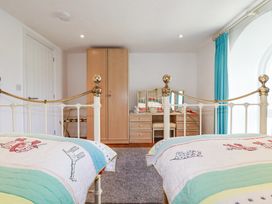 A bedroom with two beds a wooden wardrobe a dressing table with a mirror and a blue curtain at Trelowth Chapel in Polgooth