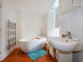 A bathroom with a freestanding bathtub a sink a towel rack and a wooden floor at Trelowth Chapel in Polgooth