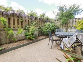 An outdoor patio with a round metal table and four chairs next to a wooden fence with plants at Trelowth Chapel in Polgooth