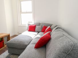 A corner of a living room with a gray sectional sofa and red cushions near a window at Seaside House in Weymouth