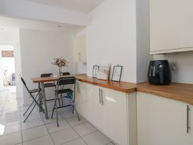 A kitchen with wooden countertops four black folding chairs a table with a vase of flowers and a black air fryer on the counter at Seaside House in Weymouth