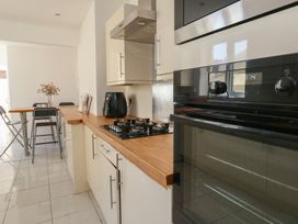 A kitchen with a built in oven and stove a black air fryer a wooden countertop and a dining table with chairs and flowers at Seaside House in Weymouth