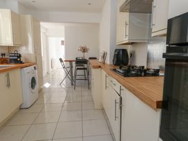 A kitchen with cream cabinets wooden countertops a washing machine and a dining table with chairs at Seaside House in Weymouth