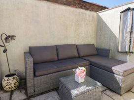 An outdoor seating area with a wicker sofa with cushions a glass top table with flowers and a decorative flower lamp at Seaside House in Weymouth