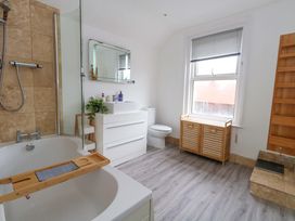 A bathroom with a bathtub, toilet, sink, and storage cabinet at Weymouth Seaside House, Weymouth