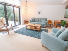 A living room with blue sofas a wooden coffee table and sliding glass doors at Chy Benyngoth in Hayle