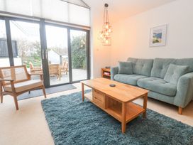 A living room with a green sofa a wooden coffee table a blue rug and large sliding glass doors at Chy Benyngoth in Hayle