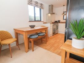 A kitchen with wooden dining table chairs and bench next to a black fridge and a stove at Chy Benyngoth in Hayle