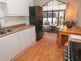 A kitchen with wooden countertops next to a dining table leading to a living area with large windows at Chy Benyngoth in Hayle
