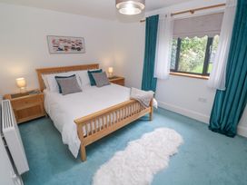 A bedroom with a wooden bed frame blue carpet white rug and blue curtains at Chy Benyngoth in Hayle