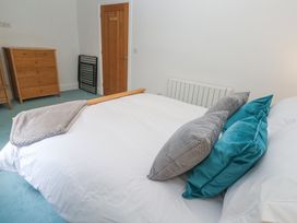 A bedroom with a bed that has pillows and a blanket a wooden dresser a wooden door and a radiator at Chy Benyngoth in Hayle