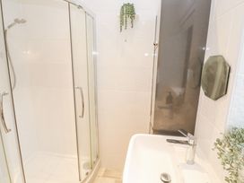 A bathroom with a shower enclosure a sink with a faucet and plants at Chy Benyngoth in Hayle