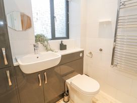 A bathroom with a sink cabinet, toilet, towel rack, and small window at Chy Benyngoth in Hayle