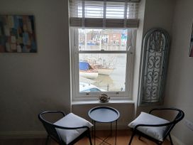 A living room with chairs and a table overlooking the harbor at Harbourside in Weymouth