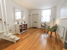 A hallway with a mirror, table, lamps, and a door at Harbourside in Weymouth