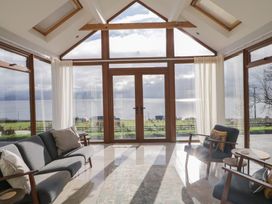 A conservatory with a sofa and armchairs overlooking a scenic view at Ard Na Mara in Drung near Quigley's Point, County Donegal