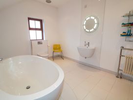 A bathroom with a bathtub, sink, toilet and chair at Ard Na Mara, Drung near Quigley's Point, County Donegal
