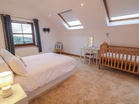 A bedroom with a bed, crib, and desk at Ard Na Mara, Drung near Quigley's Point, County Donegal