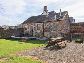 An outdoor area with a stone cottage patio table and chairs a wooden picnic table and a grass lawn at The Yarde Annexe Pen Elm near Taunton