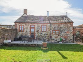 A stone cottage with a tiled roof and wooden door with windows and patio furniture on a paved area at The Yarde Annexe in Pen Elm near Taunton