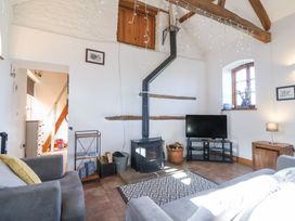 A living room with a wood burning stove television armchairs and wooden ceiling beams at The Yarde Annexe in Pen Elm near Taunton