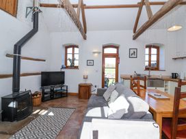 A living room with wood stove television sofa dining table and kitchen area at The Yarde Annexe Pen Elm near Taunton