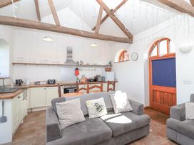 An open kitchen and living area with wooden beams a grey sofa and a kitchen with appliances at The Yarde Annexe in Pen Elm near Taunton