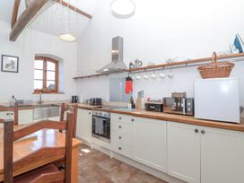 A kitchen with wooden countertops white cabinets a wooden dining table and chairs at The Yarde Annexe in Pen Elm near Taunton