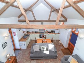 A kitchen and living area with wooden beams a dining table and sofas at The Yarde Annexe Pen Elm near Taunton