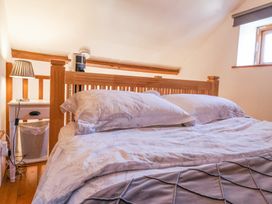 A bedroom with a wooden bed frame pillows and bedding a bedside table with a lamp and a waste bin at The Yarde Annexe Pen Elm near Taunton