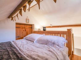 A bedroom with a wooden bed frame white floral bedding and wooden beam ceiling at The Yarde Annexe Pen Elm near Taunton