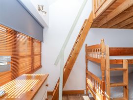 A small bedroom with wooden bunk beds a wooden chest of drawers and stairs leading to a loft at The Yarde Annexe in Pen Elm near Taunton