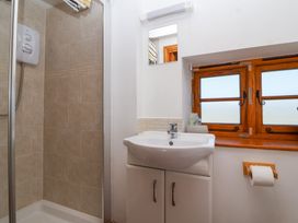A bathroom with a shower cubicle a sink cabinet a mirror a wooden window and a toilet paper holder at The Yarde Annexe Pen Elm near Taunton