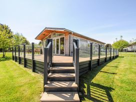 An outdoor wooden deck with glass railing and steps leading to a wooden cabin at 17 Meadow Retreat in Dobwalls