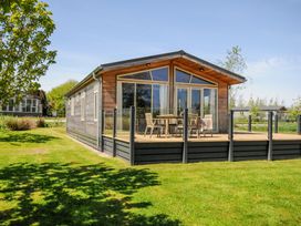 A wooden cabin with a glass enclosed deck and outdoor furniture on a grassy lawn at 17 Meadow Retreat in Dobwalls
