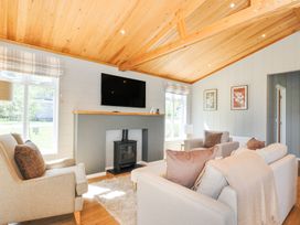 A living room with armchairs a sofa and a wood burning stove at 17 Meadow Retreat in Dobwalls