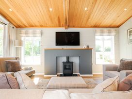 A living room with a wooden ceiling a TV mounted above a fireplace and armchairs at 17 Meadow Retreat in Dobwalls