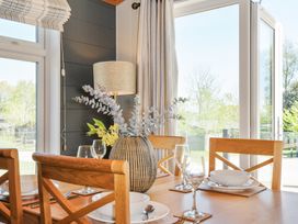 A dining table with place settings and a vase with foliage near windows with curtains at 17 Meadow Retreat in Dobwalls