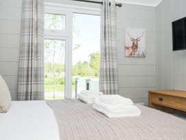 A bedroom with a bed covered in folded towels a wooden dresser a wall-mounted television and a deer painting at 17 Meadow Retreat in Dobwalls