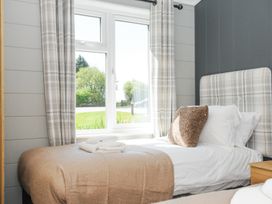 A bedroom with a single bed next to a window with plaid curtains at 17 Meadow Retreat in Dobwalls