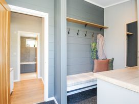 A hallway with a bench with pillows and hooks on the wall next to a bathroom at 17 Meadow Retreat in Dobwalls