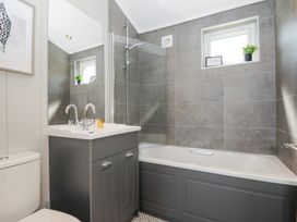 A bathroom with a bathtub shower combo and a sink vanity with mirror at 17 Meadow Retreat in Dobwalls