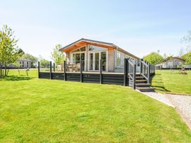 A wooden cabin with a deck and outdoor furniture on a grassy lawn at 17 Meadow Retreat in Dobwalls