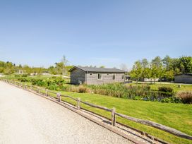 A wooden cabin near a pond with plants along a gravel pathway at 17 Meadow Retreat in Dobwalls