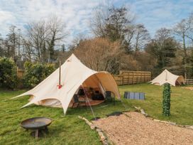 Two bell tents set up on grass with chairs a fire pit and solar panels at Bell tent 3 Camerton near Timsbury